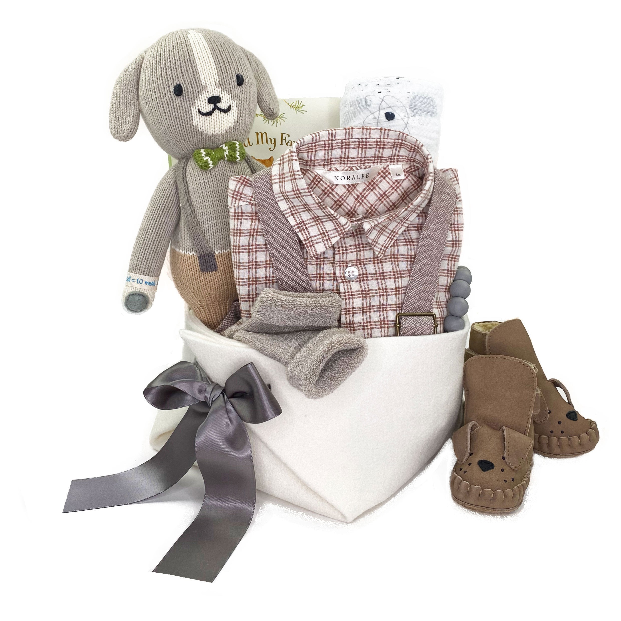 Luxury Baby Boy Gift Basket featuring Noralee suspenders pants and check shirt, leather lined boots, a doggy doll by Cuddle and Kind and curated accessories for the best baby gift at Bonjour Baby Baskets 